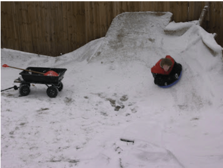 Child riding saucer sled, on a curved ramp.