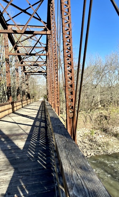 Wooden bridge over creek, connecting to trail.