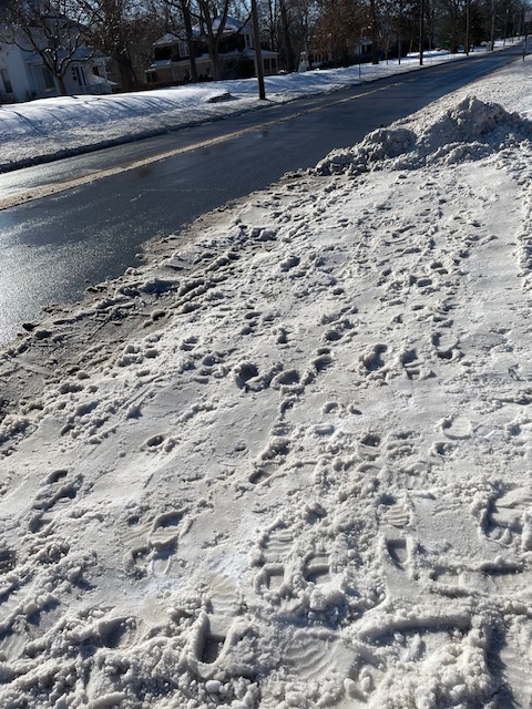 Smoothed down snow over driveway, with footprints.
