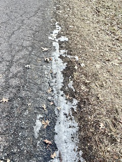 Dirty ice/snow mix between street and brown grass.