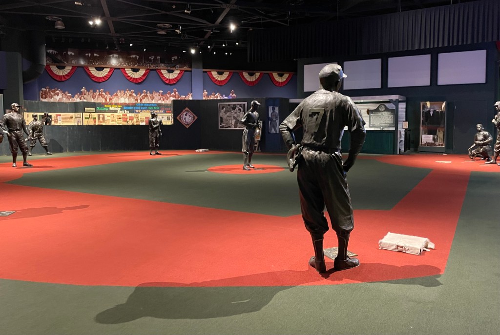 Statues of baseball players on replica ball field.